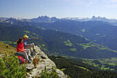 Couple resting on rim, view over valley of Eisack to Dolomites, South Tyrol, Italy
