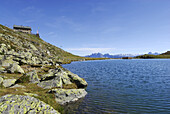 Alpine lodge above lake Radl, Dolomites in background, Sarntal Alps, South Tyrol, Italy