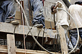 Construction workers pouring wall holding cement/concrete hose