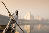 Boatman on Yamuna River with Taj Mahal in background, Agra. Uttar Pradesh, India