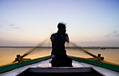 Man rowing boat on the Ganges at dawn, Varanasi. Uttar Pradesh, India