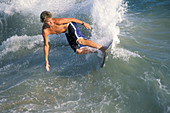 Surfer surfing on breaking wave using a skimboard, near Balboa Pier, Balboa Island, Newport Beach, California