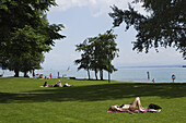 People sunbathing at lake Constance, Uberlingen, Baden-Wurttemberg, Germany