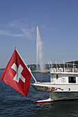 Jet d'Eau, one of the largest fountains in the world, excursion boat with Swiss flag in foreground, Lake Geneva, Geneva, Canton of Geneva, Switzerland