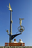 Menschen und Skulptur an der Uferpromenade unter blauem Himmel, Meersburg, Bodensee, Baden-Württemberg, Deutschland