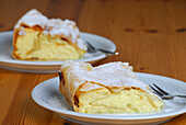 Two portions of quark strudel on plate and wooden table