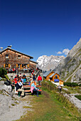 Hikers resting in front of hut Coburger Huette with view to Zugspitze range, Mieminger Gebirge range, Tyrol, Austria