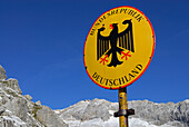 Sign of boarder Bundesrepublik Deutschland with Bundesadler at notch Gatterl with view to Zugspitze, Wetterstein range, Upper Bavaria, Bavaria, Germany
