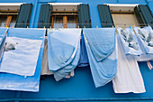 Polar bear bed covers drying on a washing line outside a blue painted house, Burano, Veneto, Italy