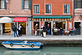 Men in conversation in front of a bar, street scene along Rio dei Vetrai Canal, Murano, Veneto, Italy