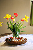 Easter decoration with easter eggs, red and yellow tulips in a vase made of glass