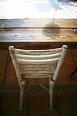 Das Sonnenlicht wirft den Schatten einer Tulpe auf einen antiken Tisch mit Stuhl