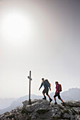 Hikers arriving summit cross, Werdenfelser Land, Bavaria, Germany