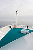 People in the bow of cruise ship AidaDiva under grey clouds