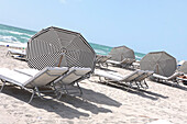 Sonnenliegen und Sonnenschirme am Strand in der Sonne, South Beach, Miami Beach, Florida, USA