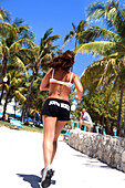 Junge Frau joggt im Lummus Park unter blauem Himmel, South Beach, Miami Beach, Florida, USA