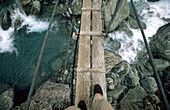 Man on a suspension bridge above the Rees Dart River, Mount Aspiring National Park, South Island, New Zealand, Oceania