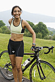 Ethnic woman in exercise clothing with bicycle in scenic setting