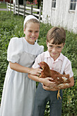 Amish Farm Tour, boy, girl, chicken. Shipshewana. Indiana. USA.