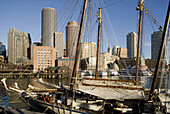 Harbor sunrise from water, two antique schooners foreground, Rowes Wharf and International Place in backgroound, Boston, Usa.