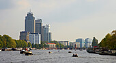 Boote fahren auf dem Fluss Amstel, Hochhäuser im Hintergrund, Amsterdam, Holland, Europa