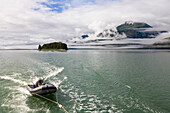 Person in a boat in front of coastline under cloud cover, Endicott Arm, Inside Passage, Southeast Alaska, USA