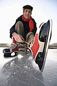 Senior man putting on ice skate, Lake Ammersee, Upper Bavaria, Germany