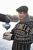 Person pouring tea into cup of senior man, lake Ammersee, Upper Bavaria, Germany