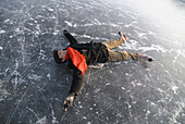 Ice skater lying on ice, Lake Ammersee, Upper Bavaria, Germany