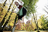 Girl wearing a dirndl, swinging in a park, Kaufbeuren, Bavaria, Germany