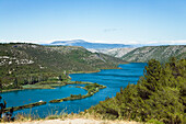 Der Fluss Krka und Berglandschaft unter blauem Himmel, Krka Nationalpark, Dalmatien, Kroatien, Europa