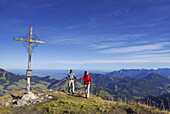 Couple reaching summit cross, Kleiner Traithen, Bavarian foothills, Bavaria, Germany