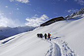 Skitourengeher beim Aufstieg zu einer Almhütte, Wiedersberger Horn, Kitzbüheler Alpen, Tirol, Österreich