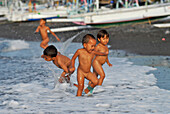 Children playing in the water at the beach, Eastern Bali, Indonesia, Asia