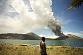 Local villager watching Tavuvur volcano in the distance, from Matupit island, Rabaul East New Britain, PNG