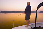 Passenger fishing before sunrise off the deck of the Schooner Nathaniel Bowditch in Holbrook Bay (part of Penobscot Bay), Maine USA