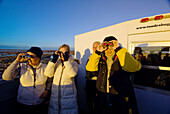 Tourists aboard a tundra buggy watch polar bears through their binoculars, along Hudson Bay, near Churchill, Manitoba, Canada