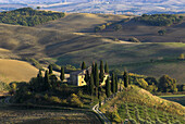 Crete with farm  in Tuscan fields, after harvest in autumn, Val d`Orcia near San Quirico, Tuscany, Italy