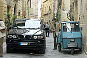 Pienza, Viale Rossellino, narrow lane, modern and traditional vehicles, de luxe car and three wheeler, Tuscany, Italy