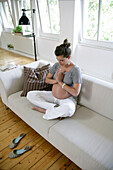 Pregnant woman meditating on sofa