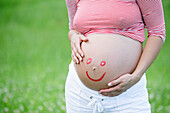 Pregnant woman with smiley face on belly