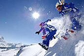 Skilehrerin und Skilehrer springen in Tiefschnee, Berglandschaft in Winter, Seiser Alm, Schlerngebiet, Südtirol, Italien