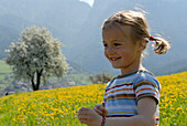 Blond girl on a flower meadow in the mountains, Völs am Schlern, South Tyrol, Italy, Europe