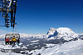 Menschen auf einem Sessellift vor schneebedeckten Bergen, Dolomiten, Südtirol, Italien, Europa