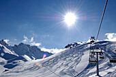 Sessellift vor schneebedeckten Bergen im Sonnenlicht, Dolomiten, Südtirol, Italien, Europa