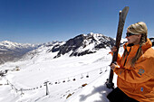 Junge Frau mit Ski an einer Skipiste unter blauem Himmel, Schnalstal, Vinschgau, Südtirol, Italien, Europa
