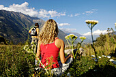 Ein junges Paar rastet auf einer Wiese mit Blick ins Tal, Vinschgau, Südtirol, Italien, Europa