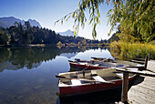 Lake with rowing boats and reflection, Lago di Fie, view to Monte Sciliar, Dolomite Alps, South Tyrol, Italy