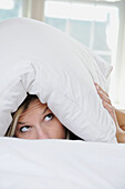 woman under pillow scared