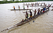 Papuan tribesmen paddling long boat, Indonesia